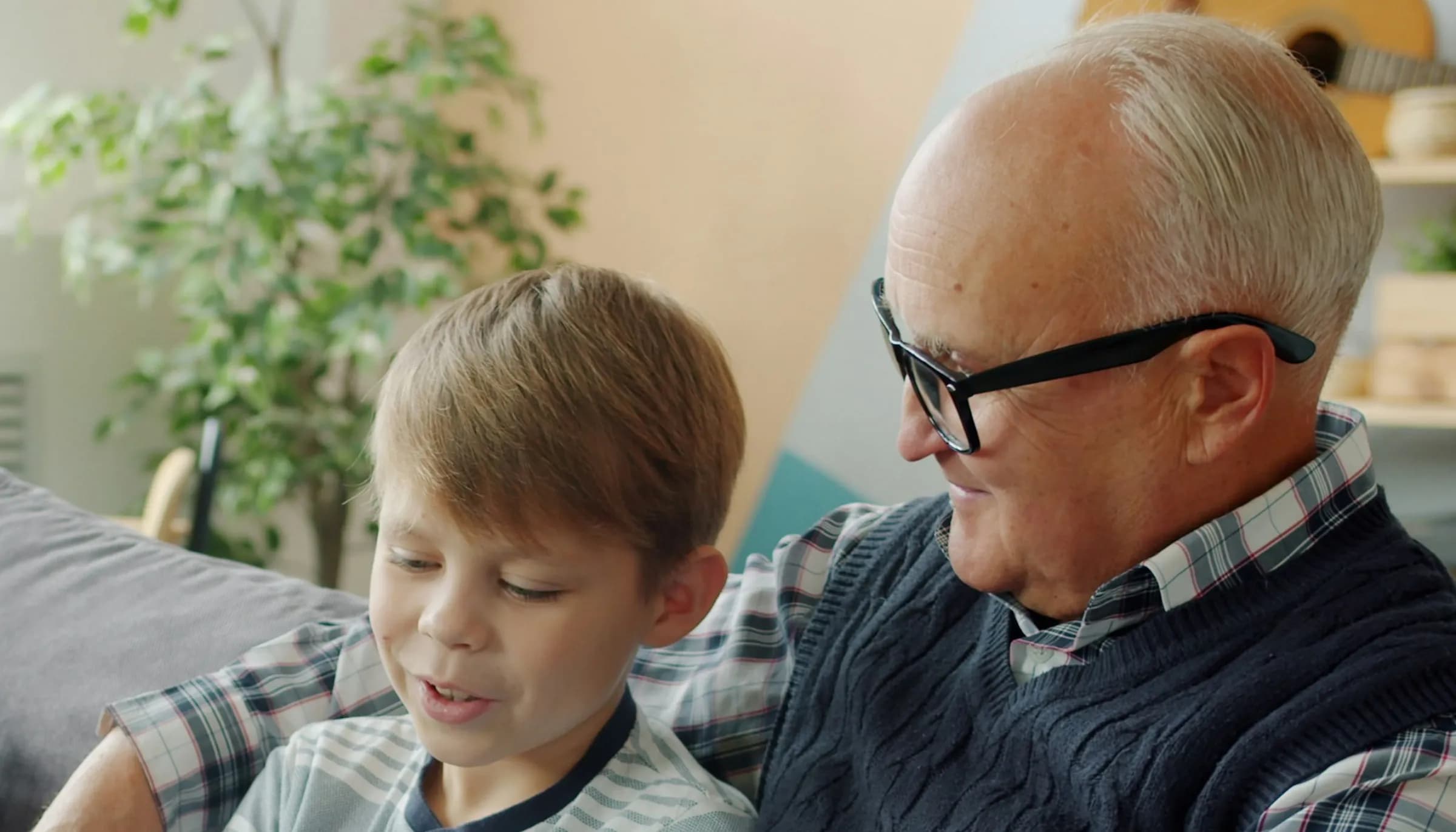 A grandfather and his grandson talk together on the sofa